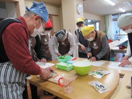 ダンディキッチンの様子、高齢者男性複数名が料理教室で料理をしている