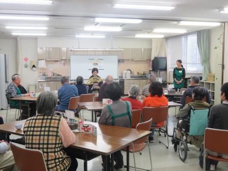 にこにこ丸山カフェ、高齢者複数名が室内でゲストの話を聞いている