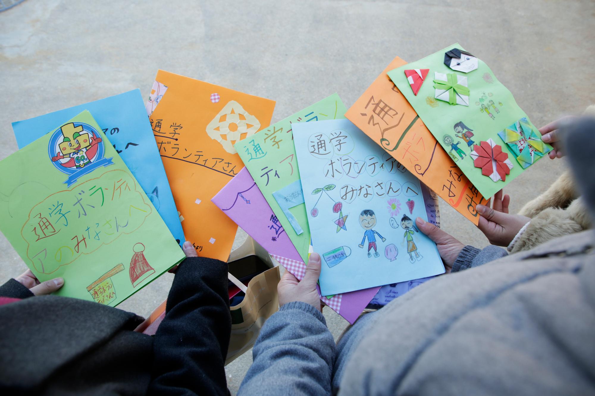 児童から通学ボランティアをした大学生へ向けて贈られた文集が写った写真。文集の紙は色とりどりで、クレヨンや色鉛筆で絵が描かれたり、折り紙が貼られているものもある。